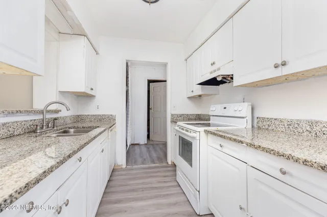 a kitchen with granite countertop white cabinets and white appliances