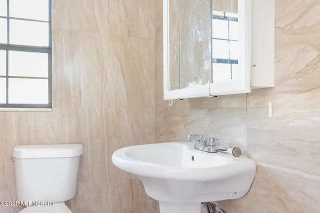 a bathroom with a sink a toilet and a window