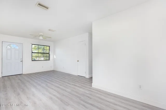 an empty room with wooden floor cabinet and windows