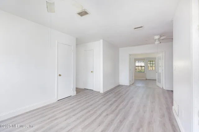 a view of an empty room with window and wooden floor