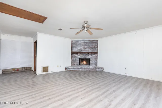a view of empty room with wooden floor and fireplace