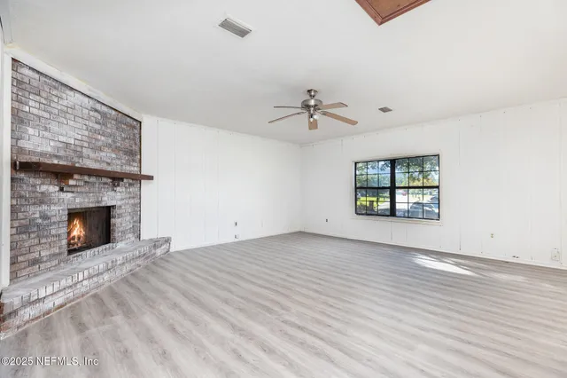an empty room with windows and fireplace