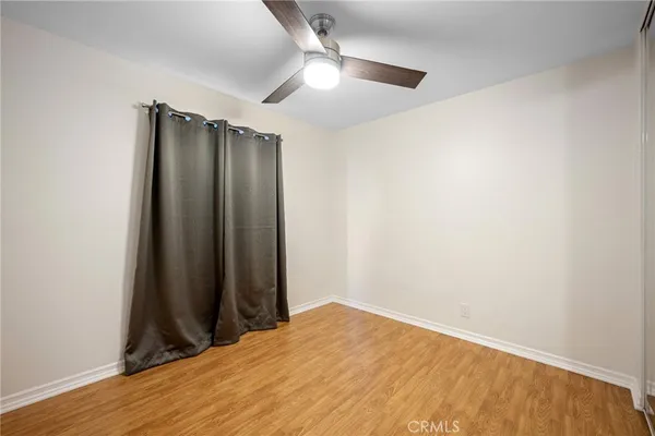 an empty room with wooden floor and a ceiling fan