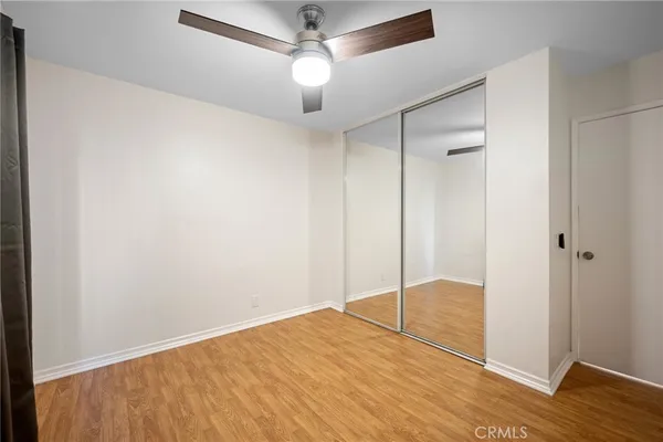a view of empty room with wooden floor and fan