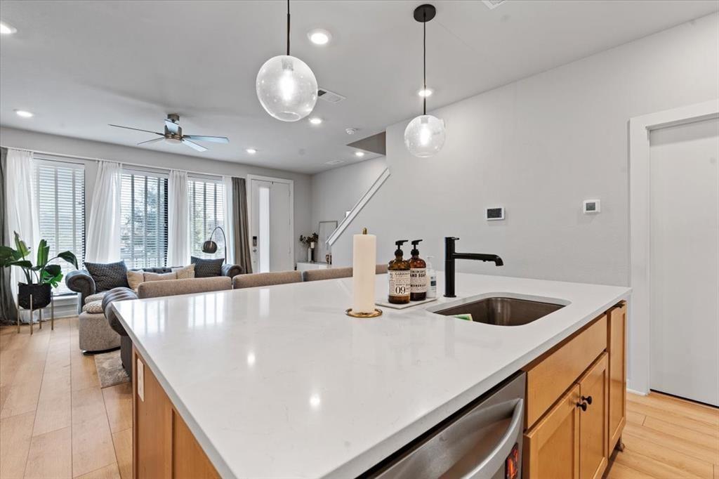 2268 Rook Drive Dallas, TX 75211 - Photo 3 of 13 Modern kitchen island featuring a white countertop, an undermount sink with a matte black faucet, and light wood cabinetry with stainless steel appliances