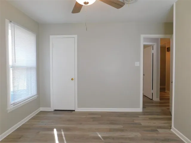a view of an empty room with window and wooden floor