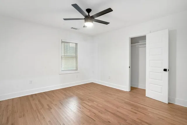 an empty room with wooden floor and windows