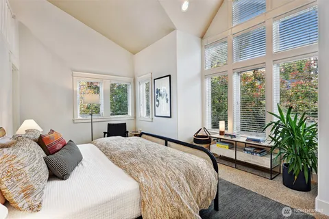 a bedroom with a bed and large windows