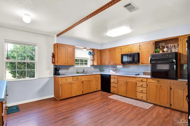 a kitchen with granite countertop a stove top oven sink and cabinets