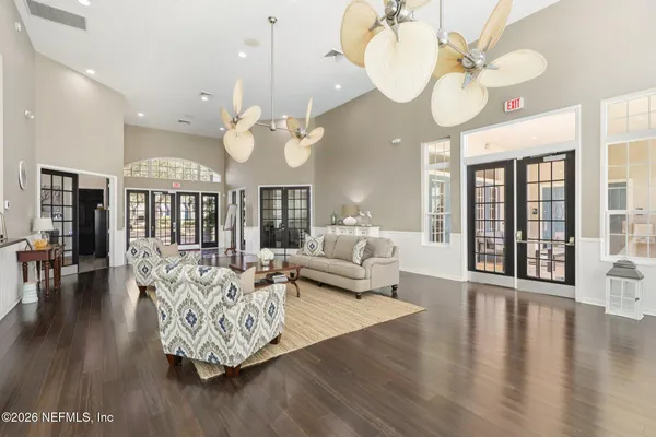 a living room with couches chandelier and a dining table with wooden floor