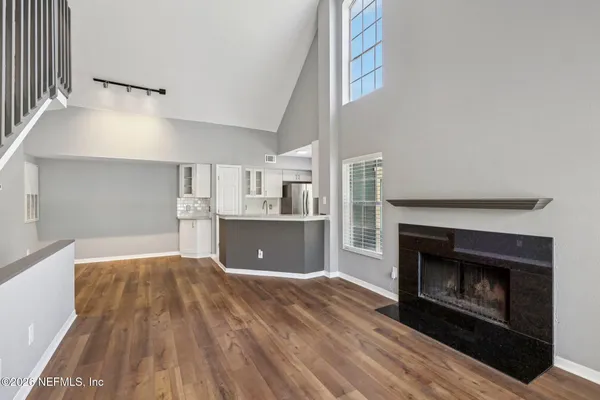 a view of kitchen and empty room with wooden floor