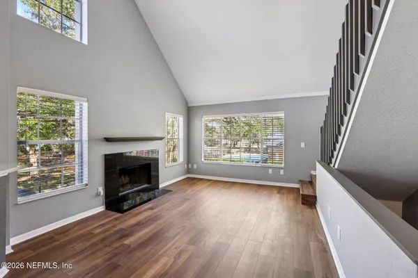 a view of an empty room with wooden floor fireplace and a window