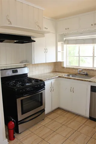 a white kitchen with granite countertop a stove top oven
