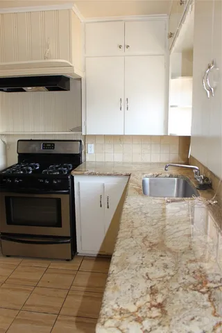 a kitchen with granite countertop a stove a sink and cabinets