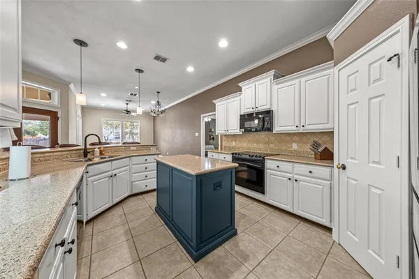 a large kitchen with granite countertop lots of white cabinets