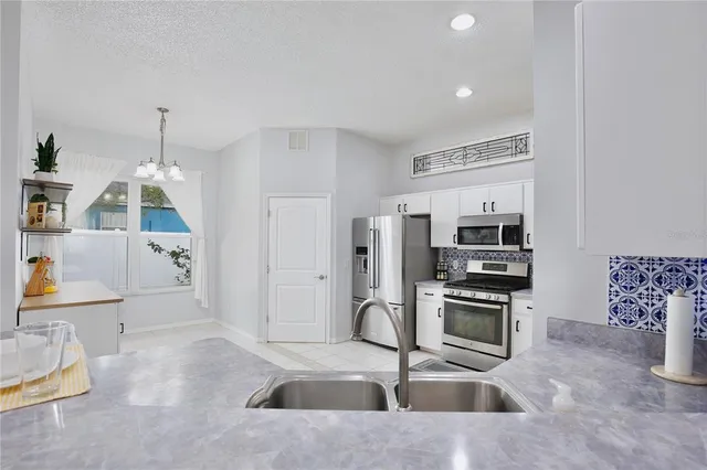 a kitchen with kitchen island granite countertop a sink and white cabinets with wooden floor