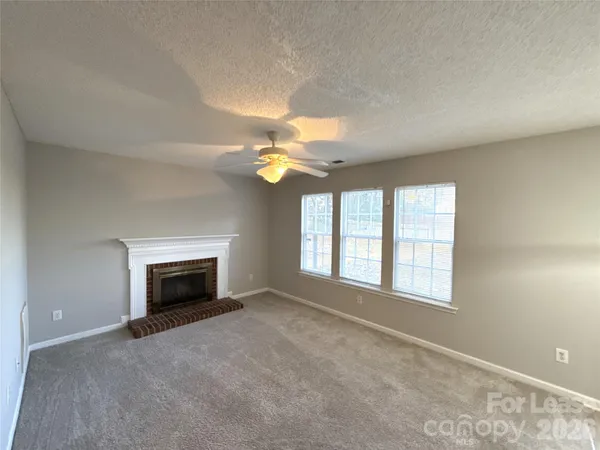 an empty room with windows and fireplace