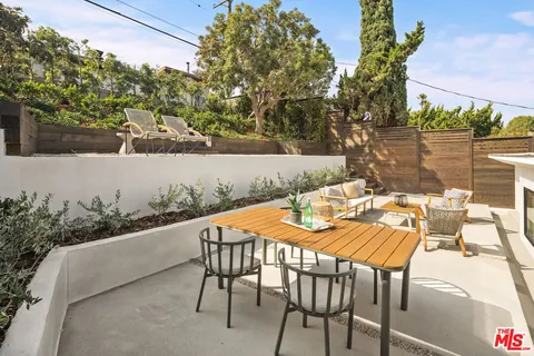 a patio with table and chairs and potted plants