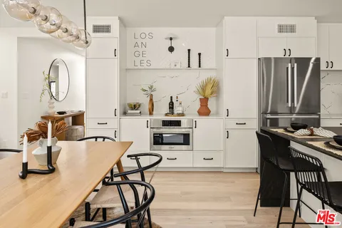 a living room with stainless steel appliances furniture a clock and a table