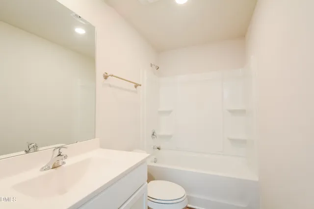 a bathroom with a bathtub shower sink vanity and toilet