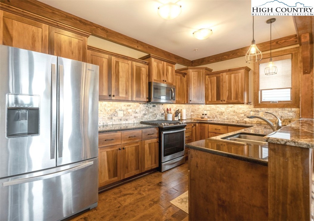 171 Falcon Trace, Unit C411 Boone, NC 28607 - Photo 6 of 46 a kitchen with stainless steel appliances granite countertop a refrigerator a sink dishwasher a stove and white countertops with wooden floor