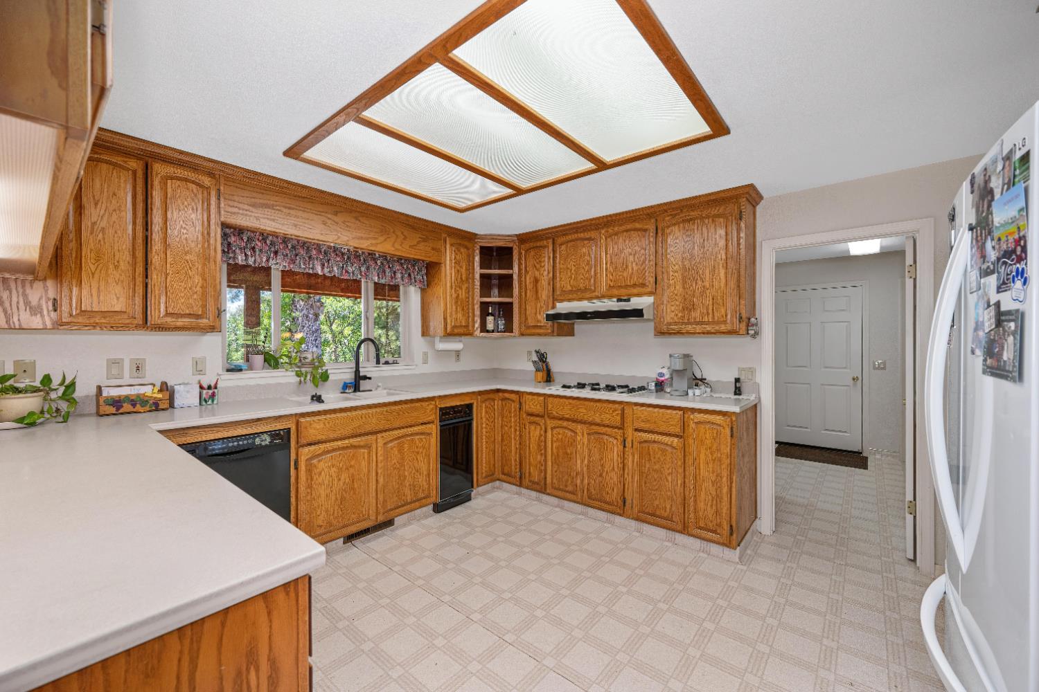 5215 Faraway Road Greenwood, CA 95635 - Photo 11 of 46 kitchen with light floors, wood finish cabinetry, freestanding refrigerator, light countertops, and black dishwasher