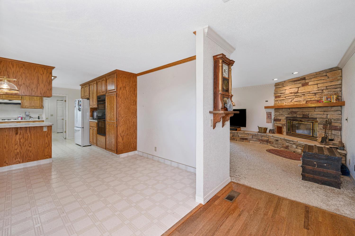 5215 Faraway Road Greenwood, CA 95635 - Photo 13 of 46 kitchen with crown molding, wood finish cabinets, a fireplace, freestanding refrigerator, and light countertops