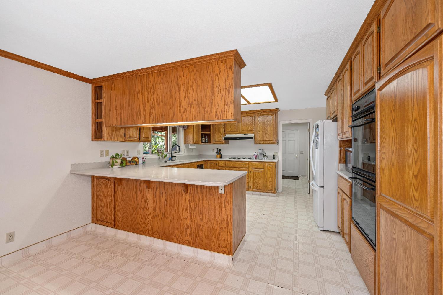 5215 Faraway Road Greenwood, CA 95635 - Photo 15 of 46 kitchen featuring a peninsula, wood finish cabinetry, light countertops, light flooring, and ornamental molding