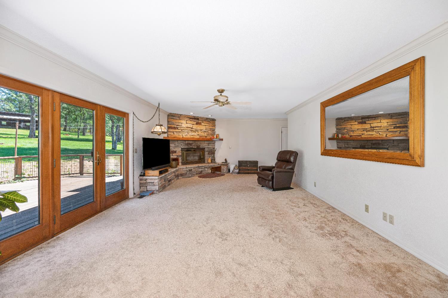 5215 Faraway Road Greenwood, CA 95635 - Photo 16 of 46 unfurnished living room with ornamental molding, ceiling fan, carpet flooring, and a stone fireplace