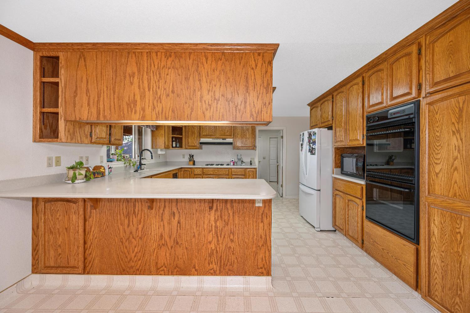 5215 Faraway Road Greenwood, CA 95635 - Photo 9 of 46 kitchen featuring light floors, wood finish cabinetry, open shelves, a peninsula, and light countertops
