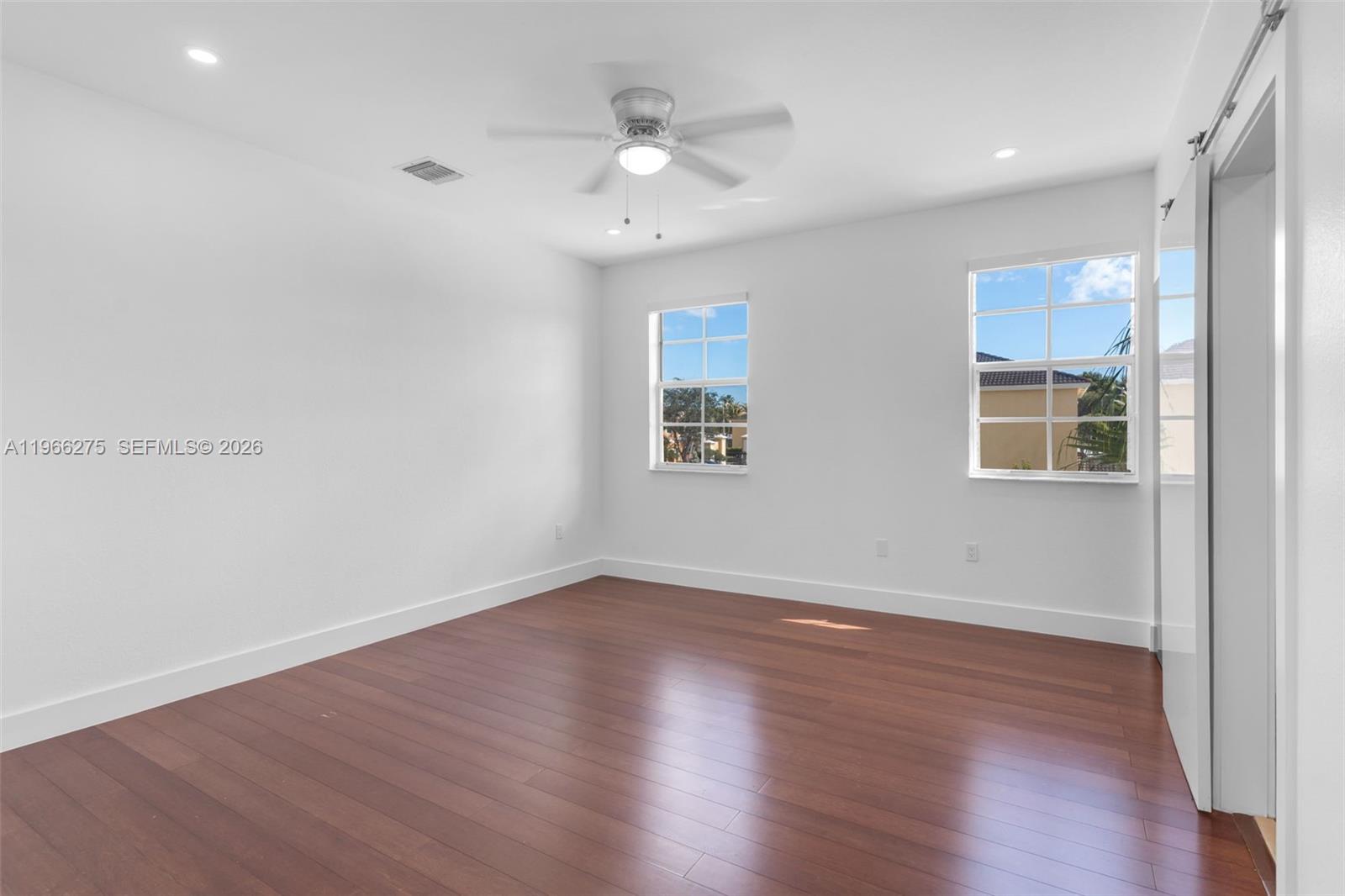 30 Southeast 6th Road Homestead, FL 33030 - Photo 19 of 34 a view of an empty room with wooden floor and a ceiling fan