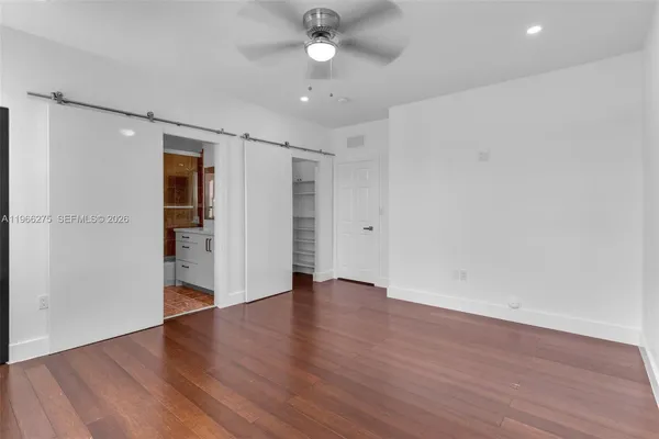 an empty room with wooden floor a ceiling fan and windows
