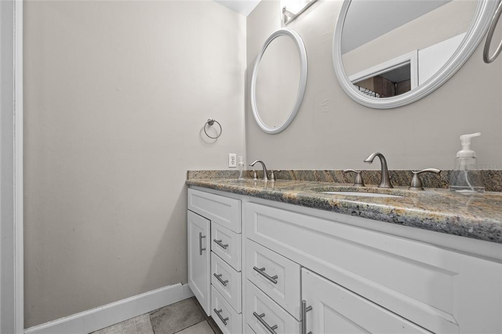 2601 Southwest Archer Road, Unit 334 Gainesville, FL 32608 - Photo 23 of 31 a bathroom with a granite countertop double vanity sink and a mirror