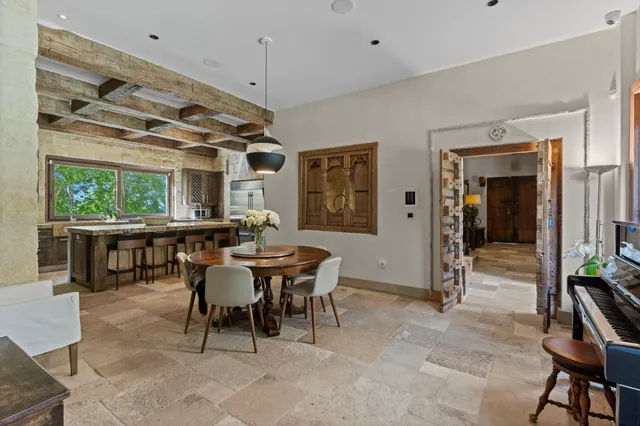 a dining room with wooden floor a chandelier a glass table and chairs