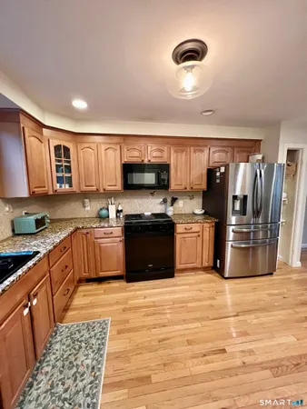 a kitchen with stainless steel appliances granite countertop a stove a sink dishwasher a refrigerator and a oven with wooden floor
