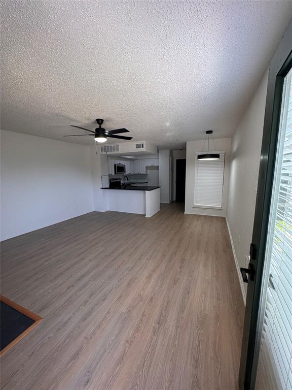 2305 Basil Drive, Unit D108 Arlington, TX 76006 - Photo 3 of 23 Unfurnished living room featuring light wood-style floors, ceiling fan, and a textured ceiling