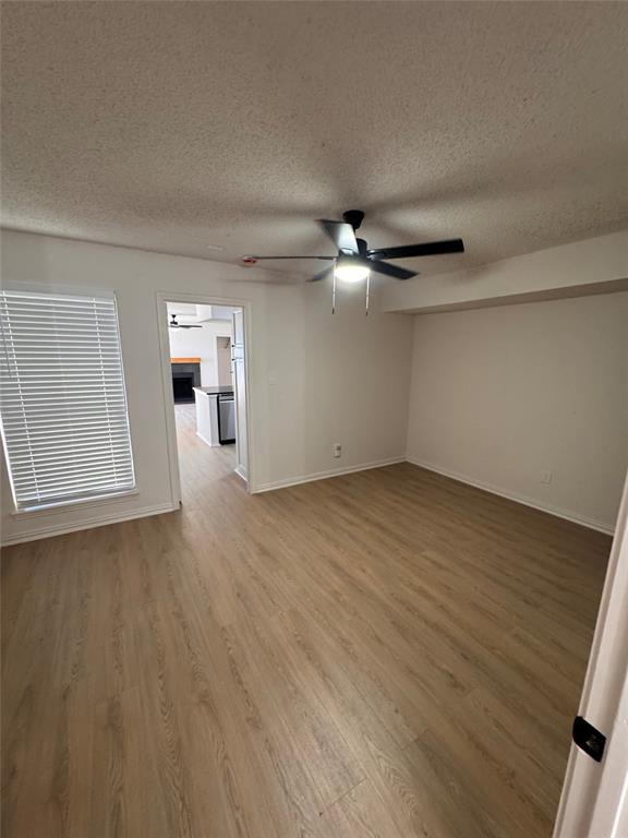2305 Basil Drive, Unit D108 Arlington, TX 76006 - Photo 6 of 23 Empty room with light wood-type flooring, a textured ceiling, and a ceiling fan