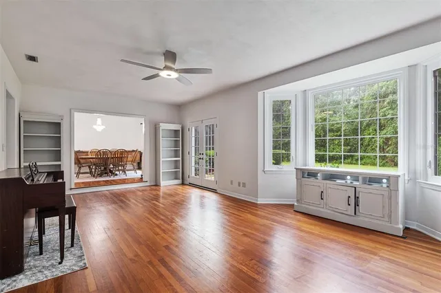 a view of an empty room with wooden floor fireplace and a window