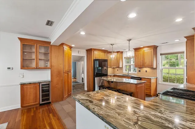 a kitchen with stainless steel appliances granite countertop a stove a sink a refrigerator and a dining table