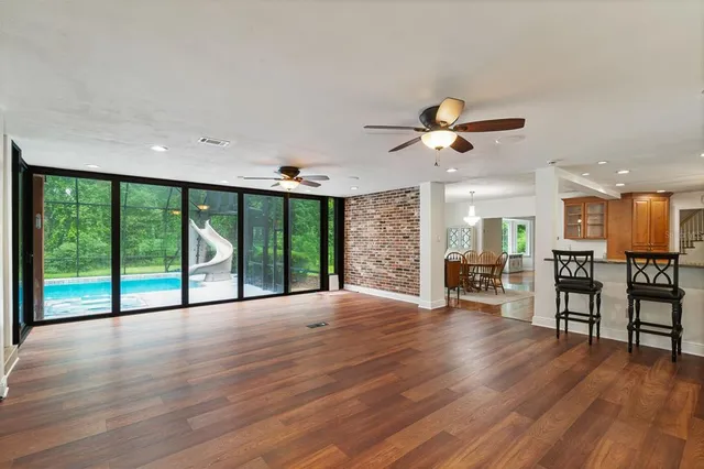 an empty room with wooden floor chandelier fan and windows