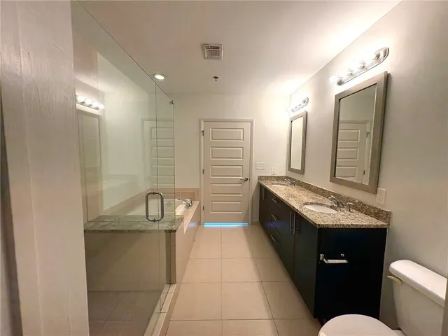 a bathroom with a granite countertop sink a toilet a mirror and bathtub