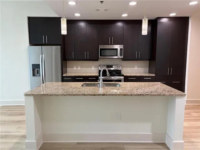 a kitchen with kitchen island stainless steel appliances a sink and a refrigerator