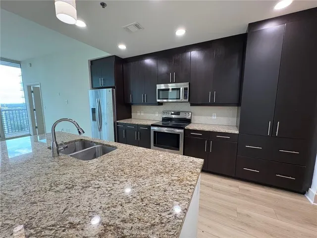 a kitchen with stainless steel appliances granite countertop a sink a stove top oven a refrigerator and dishwasher