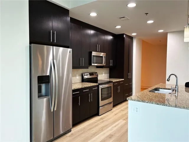 a kitchen with stainless steel appliances granite countertop a refrigerator a stove a sink and a microwave