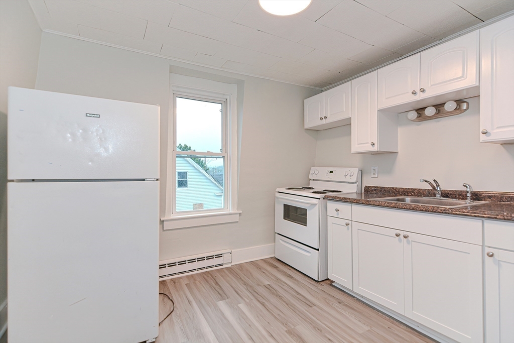 2-6 North Main Street Rochester, NH 03867 - Photo 23 of 40 a kitchen with granite countertop white cabinets and white appliances