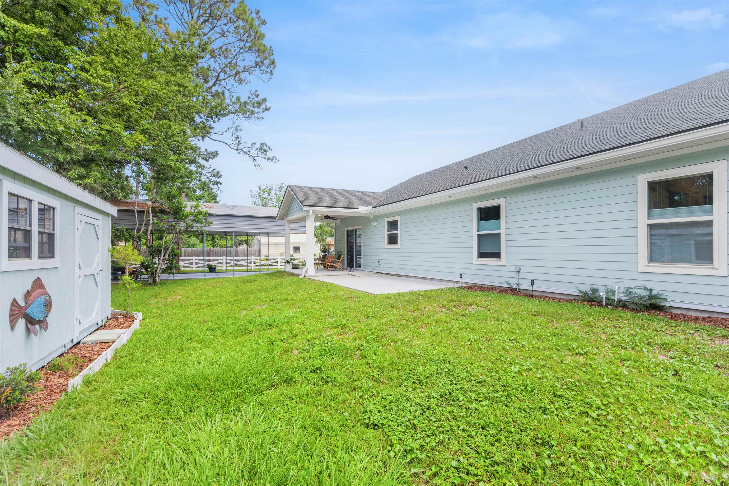 6779 Magnolia Lane St. Augustine, FL 32086 - Photo 38 of 61 Rear view of house with a patio, a shingled roof, a yard, and an outbuilding