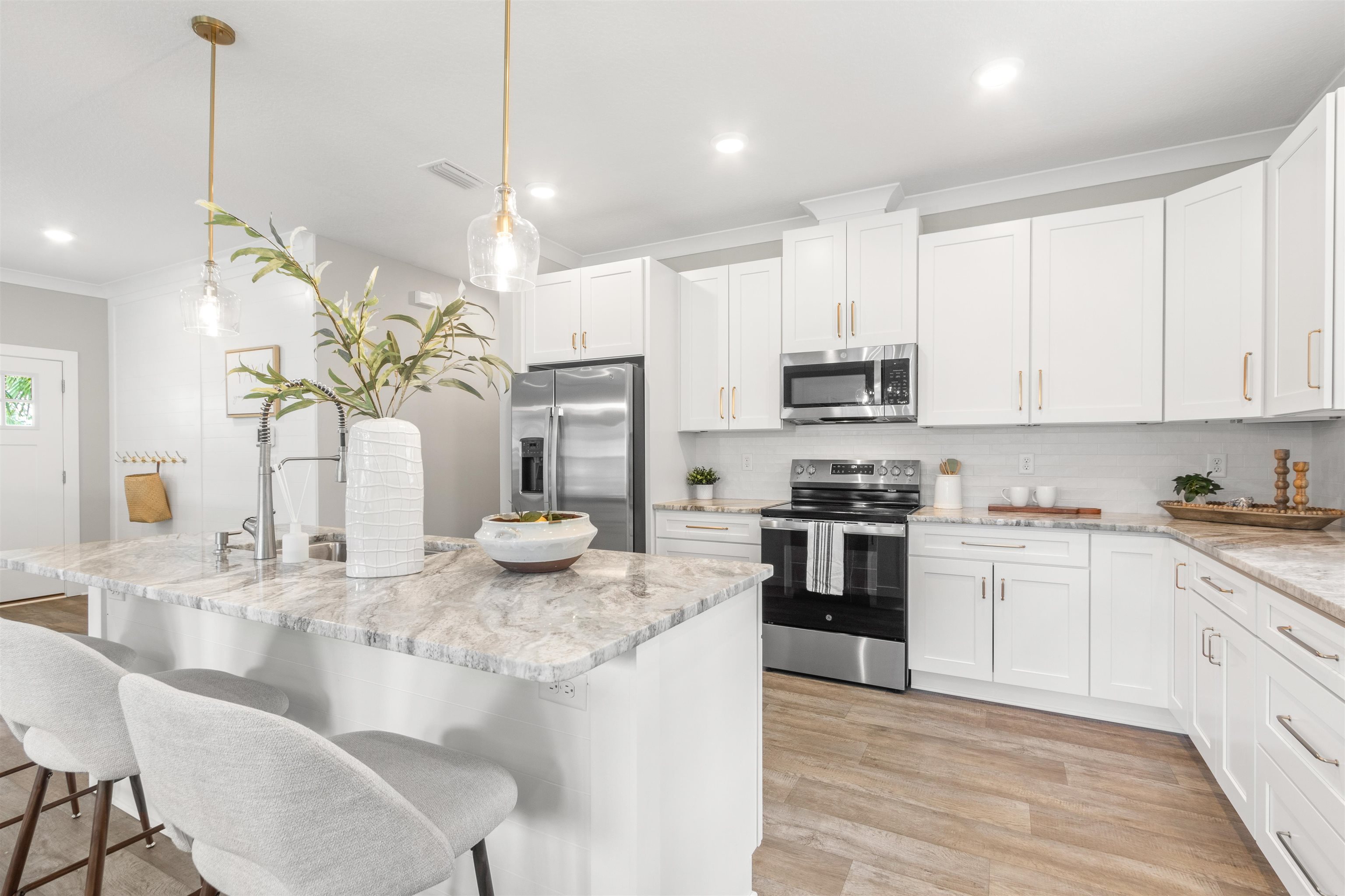 6779 Magnolia Lane St. Augustine, FL 32086 - Photo 10 of 61 Kitchen with white cabinetry, appliances with stainless steel finishes, backsplash, an island with sink, and crown molding