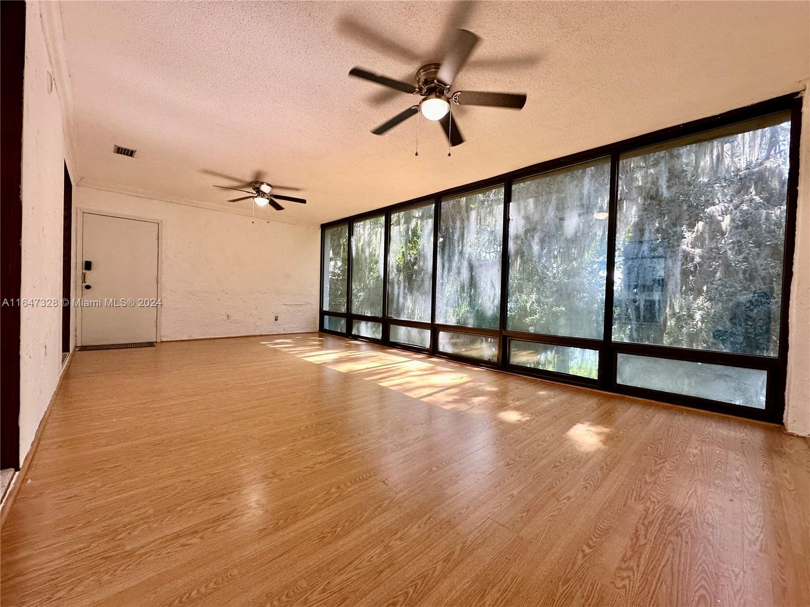 2816 Southwest 14th Drive, Unit 2816 Gainesville, FL 32608 - Photo 2 of 14 a view of an empty room with wooden floor and a window