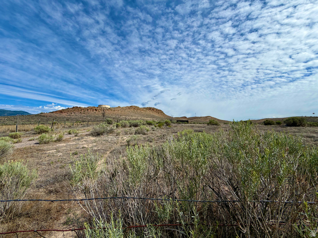 600 East E Street Moroni, UT 84646 - Photo 2 of 38 Expansive land parcel featuring natural desert flora, distant rolling hills, and a prominent mesa formation