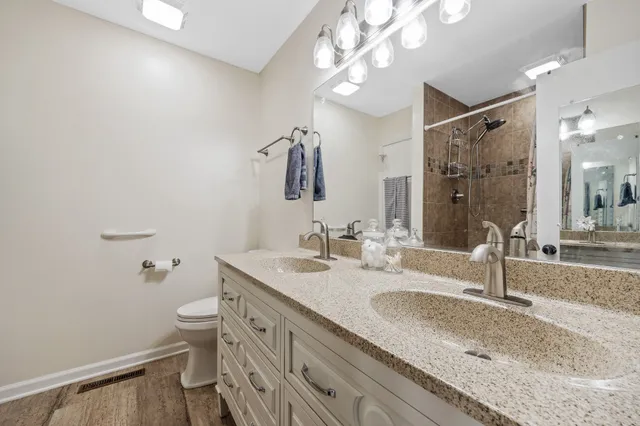 a bathroom with a granite countertop sink a toilet a mirror and shower